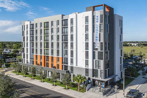 A modern multi-story building with a sign that reads "NOW LOW LEASING".