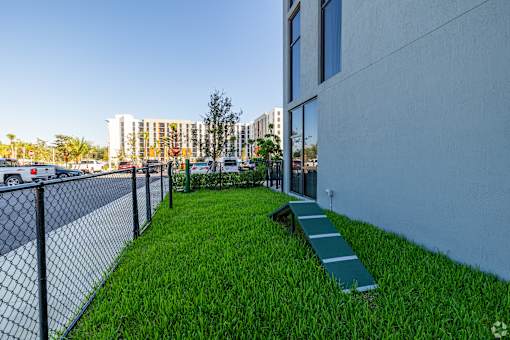 A grassy area with a bench and a fence in front of a building.
