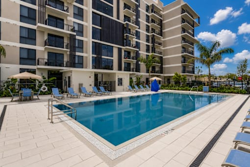 A large swimming pool in front of a multi-story apartment building.