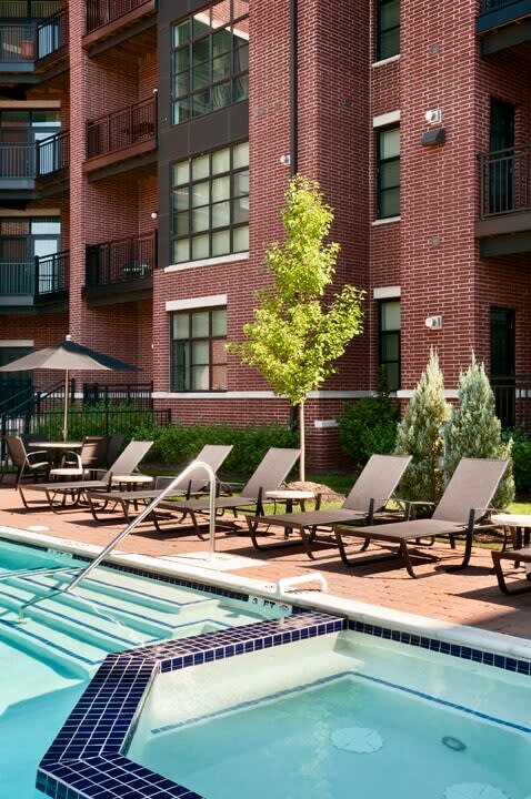 a swimming pool with chaise lounge chairs in front of a brick building  at The Sheffield Englewood, Englewood