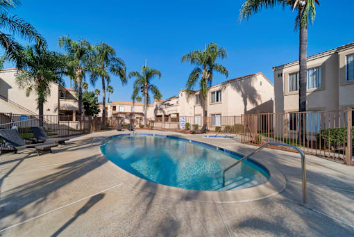 A swimming pool surrounded by palm trees and residential buildings.