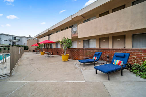 A patio with blue chairs and a red umbrella.
