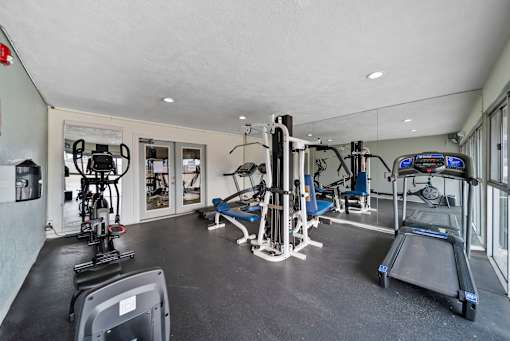 A gym with a variety of equipment including treadmills, weights, and exercise machines.
