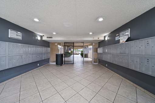 A hallway with lockers on both sides and a trash can in the middle.