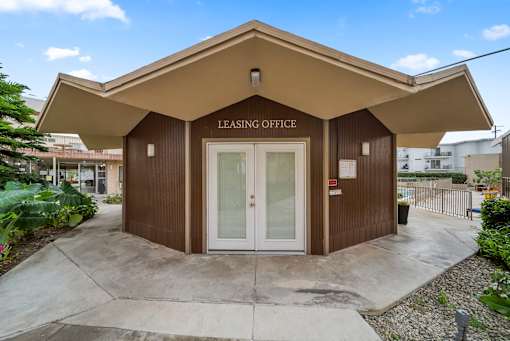 A small building with a brown roof and a sign that says "Leasing Office".