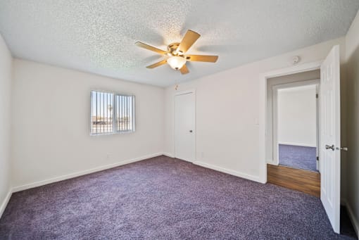 A room with a ceiling fan and a window with blinds.