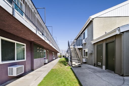 A long, narrow courtyard between two buildings with a staircase in the middle.