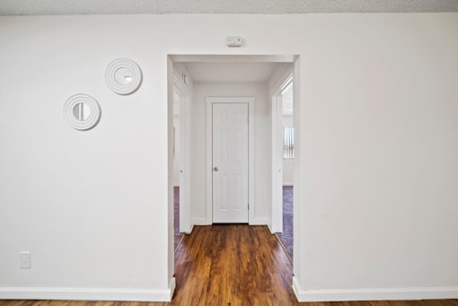 A white door is in a white room with a light switch on the wall.