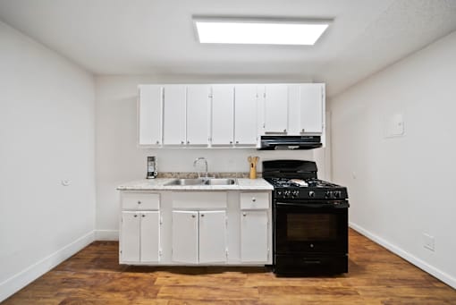 A kitchen with white cabinets and a black stove top oven.