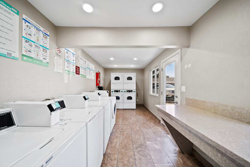 A laundromat with washers and dryers lined up.