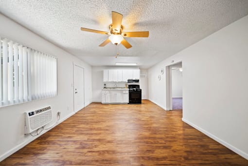 A room with a ceiling fan and wooden floors.