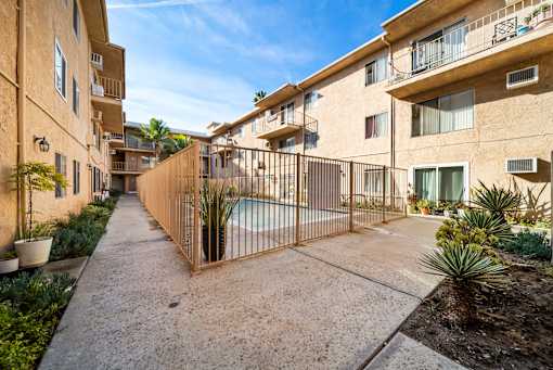 A sunny day at a residential complex with a pool and a fence.
