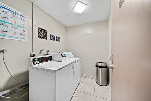 A clean, white medical room with a sink and a trash can.