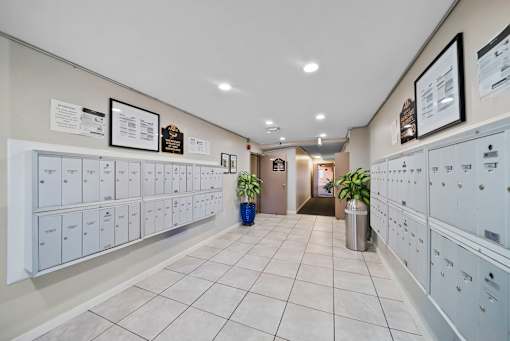 A hallway with white lockers and a blue trash can.