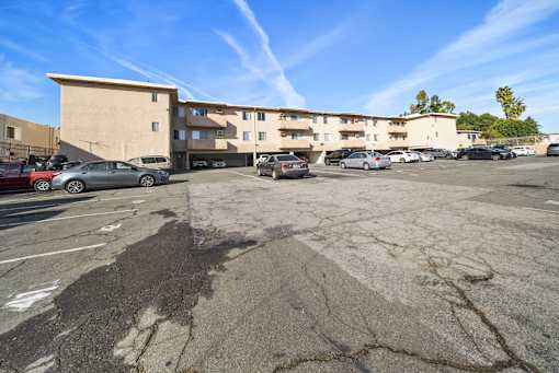 A parking lot with a building in the background and several cars parked.