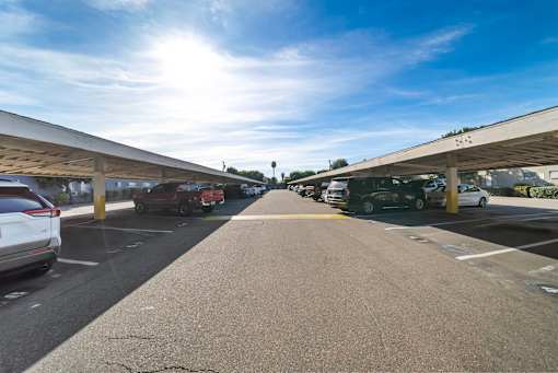 A parking lot with cars parked under a covered area.