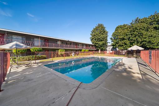 A swimming pool in front of a building with a red fence.