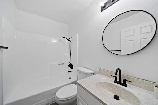 A bathroom with a toilet, sink, and mirror.