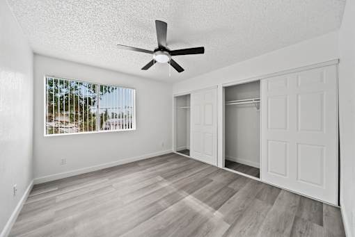 A room with a ceiling fan and a window with blinds.