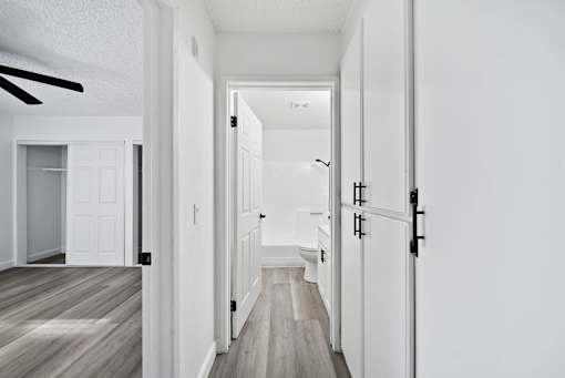A long hallway with white walls and wood floors.