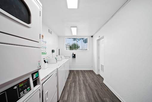 A long white hallway with a washing machine on the left.