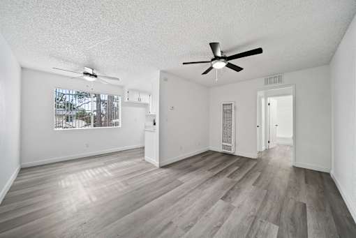 A room with a ceiling fan and a window with a view of trees and a building.
