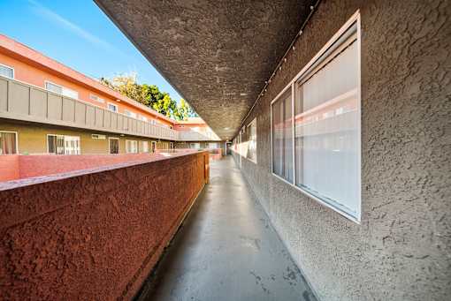 A long hallway with a red wall on the left and a concrete wall on the right.