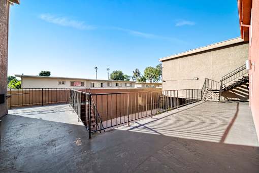 A courtyard with a metal railing and a staircase leading to a building.