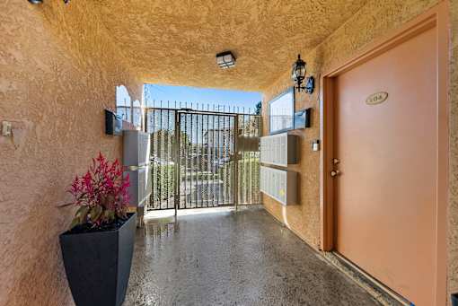 A hallway with a brown door and a black planter on the floor.