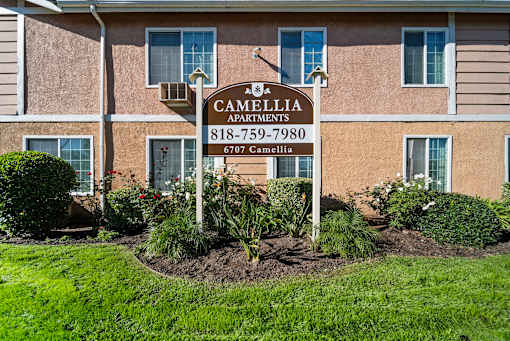 A sign for Cambellia Apartments stands in front of a building.