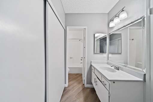 A white bathroom with a sink, mirror, and towel rack.