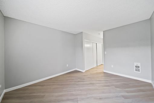 A room with a white door and wooden flooring.
