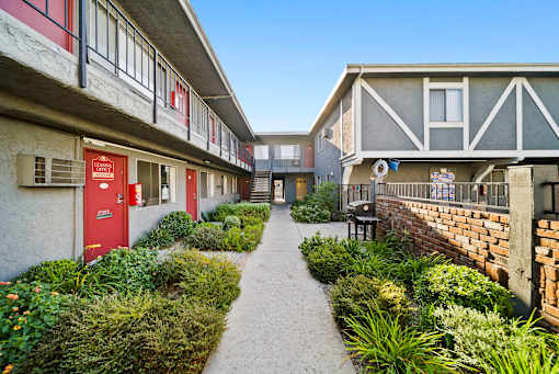 A pathway leads between two buildings with red doors.