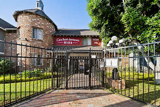 A black iron gate leads to a brick building with a sign that says Casa Royal Apartments.