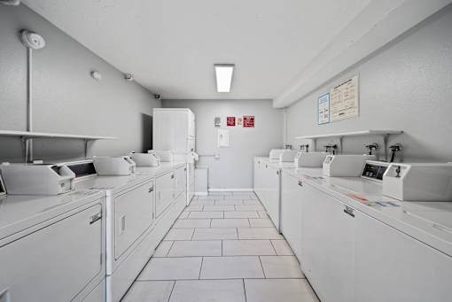 A row of white washing machines in a laundromat.