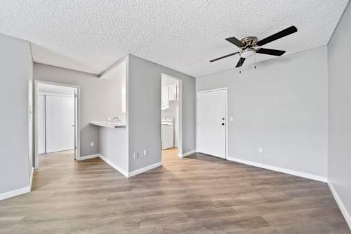 A spacious room with a ceiling fan and light wood flooring.