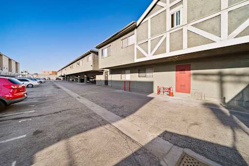 A parking lot with a red car and a building with a red door.