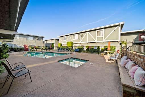 A pool surrounded by chairs and a fence.