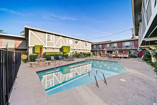 A swimming pool surrounded by a fence and chairs.