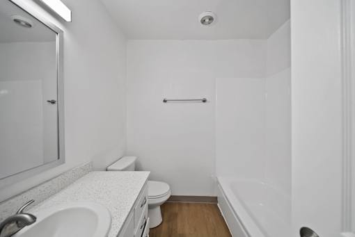 A white bathroom with a toilet, sink, and bathtub.