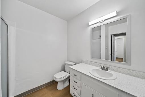 A white bathroom with a toilet, sink, and mirror.