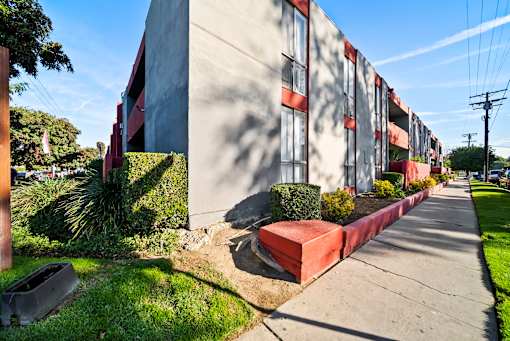 A long building with red trim and a red planter box on the side.