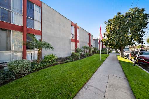 A long concrete walkway leads to a building with red trim.