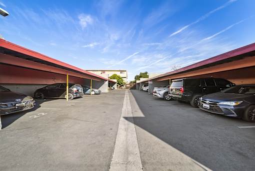 A parking lot with cars parked under a red roof.