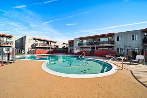 A round above ground pool with a white border and a brown sandy area around it.
