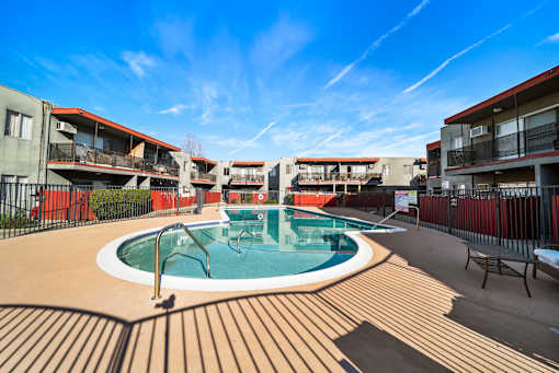 A swimming pool surrounded by a wooden deck and buildings.