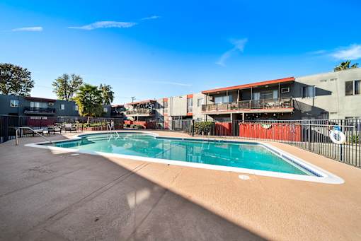 A swimming pool surrounded by a fence and buildings.
