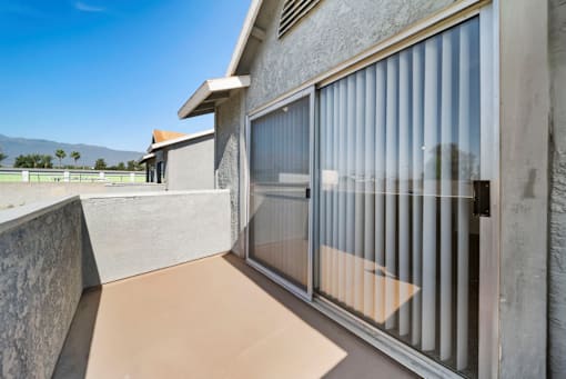 A patio with a sliding glass door and a concrete wall.