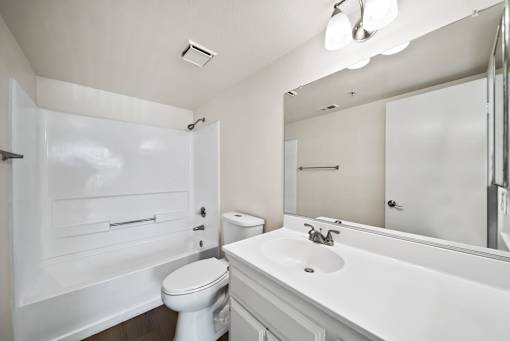 A white bathroom with a toilet, sink, and mirror.