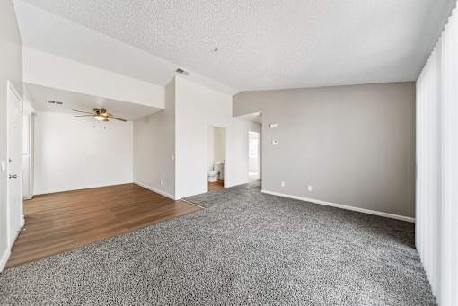 A spacious room with a ceiling fan and carpeted floor.